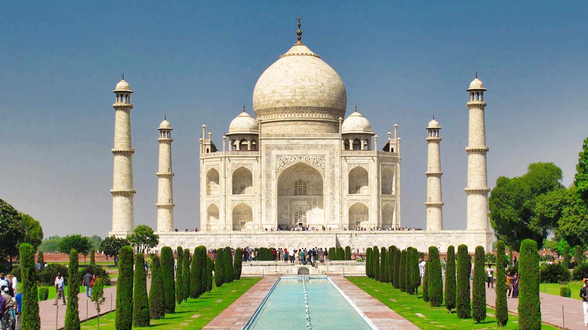 a large white building with a pool of water and trees with Taj Mahal in the background